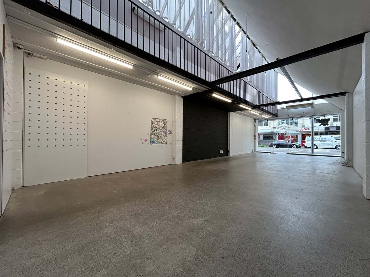 Modern commercial space interior with high ceilings and large glass windows.