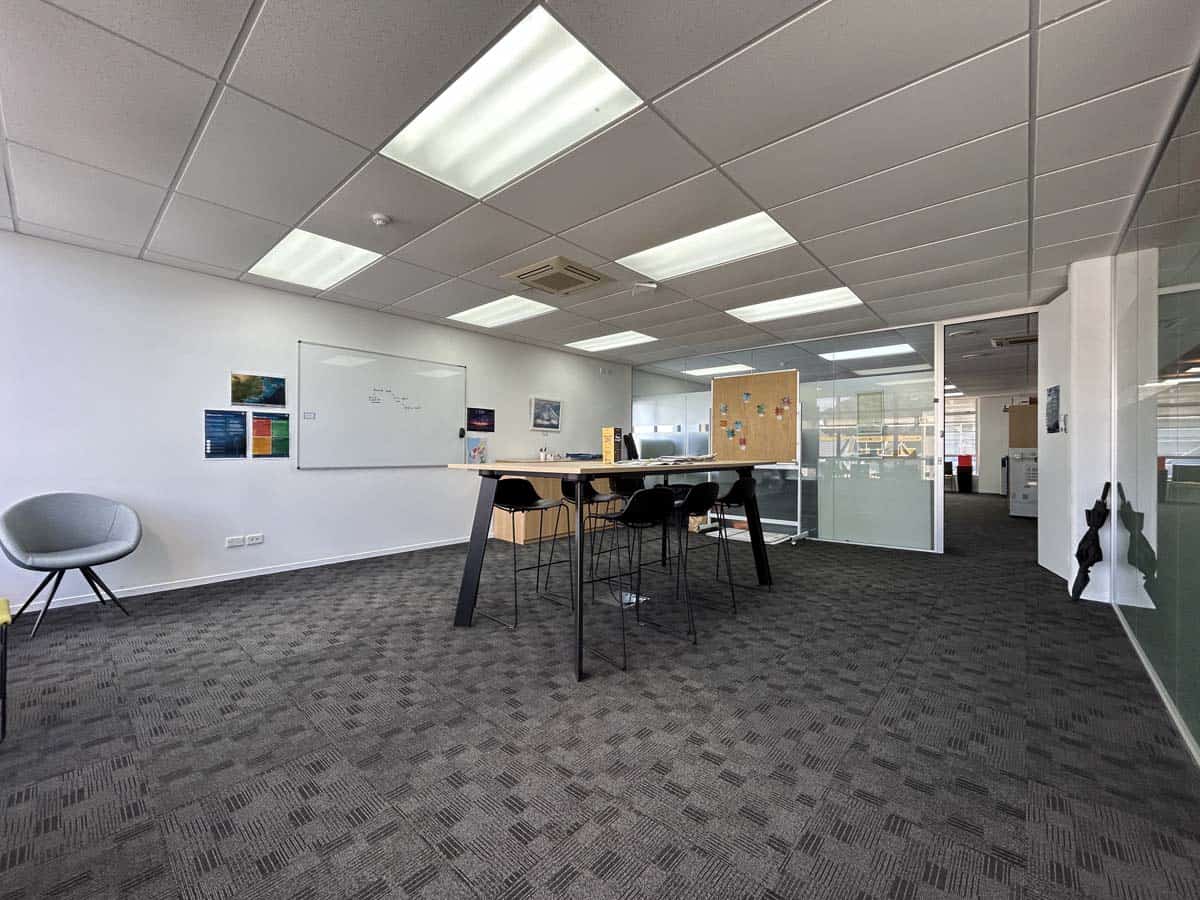 Contemporary office space with meeting table, whiteboard, and glass walls.