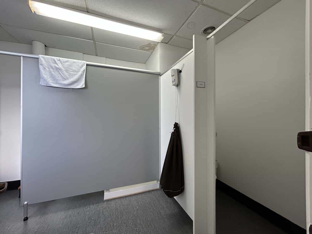 Office cubicle with towel hanging on partition and coat on hook in workspace.