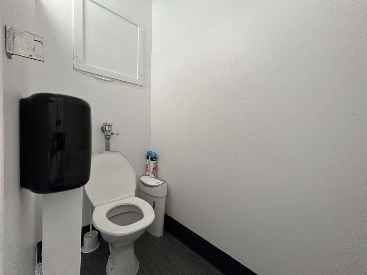 Toilet and hand sanitizer in a clean, minimalistic bathroom setting.