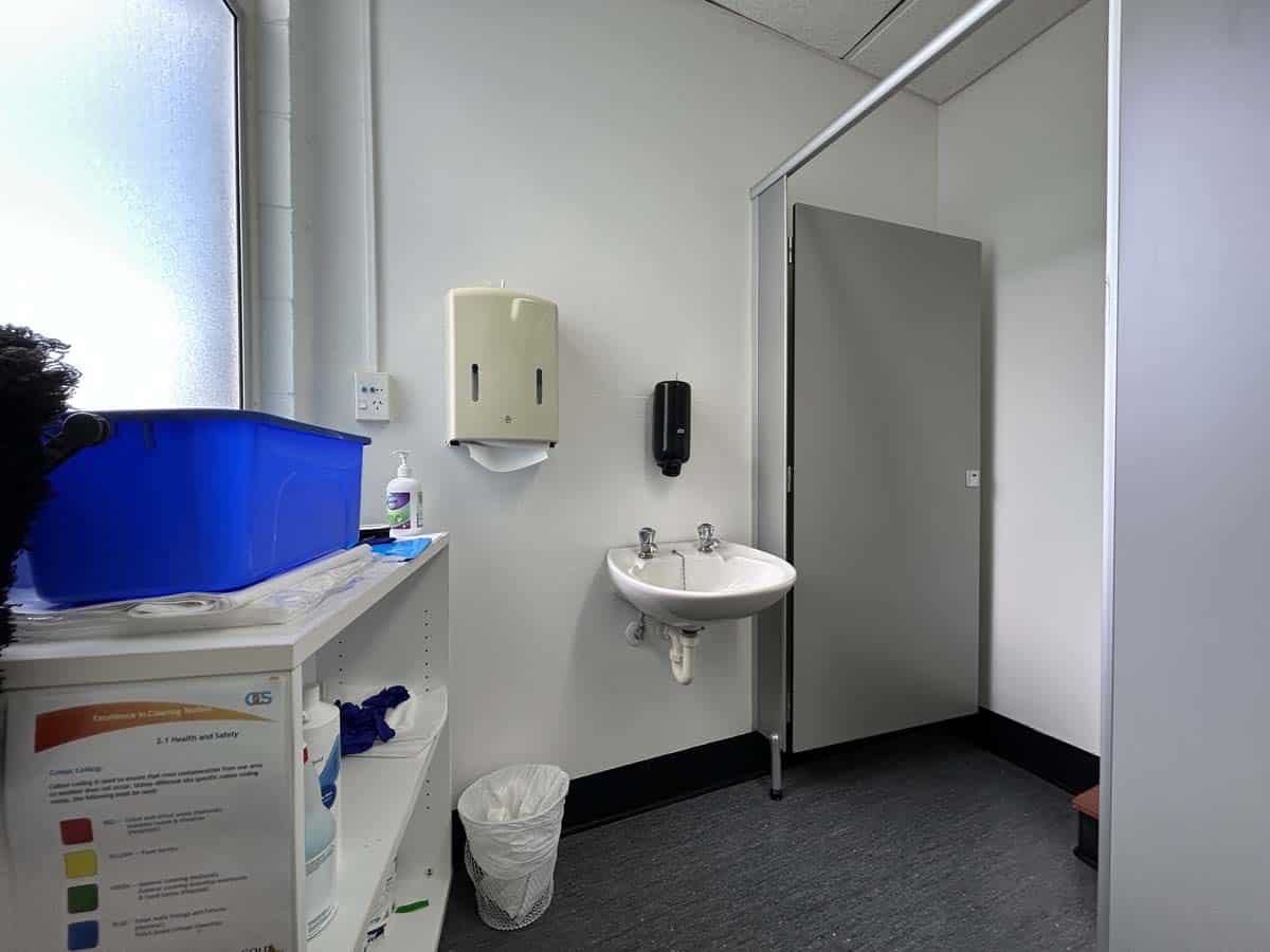 Modern public restroom with sink, hand sanitizer, and privacy cubicle.
