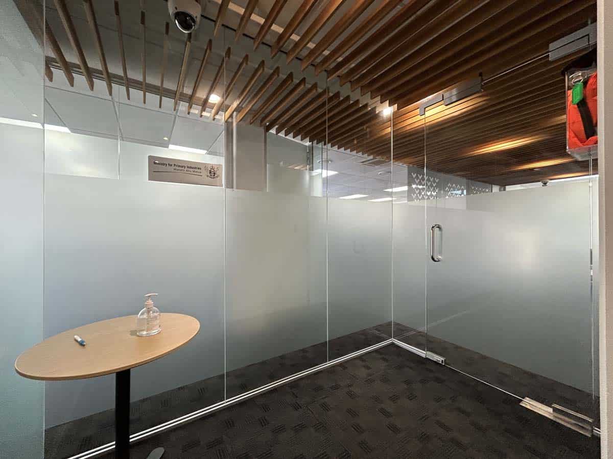 Interior view of a modern office meeting room with glass walls and wooden ceiling.