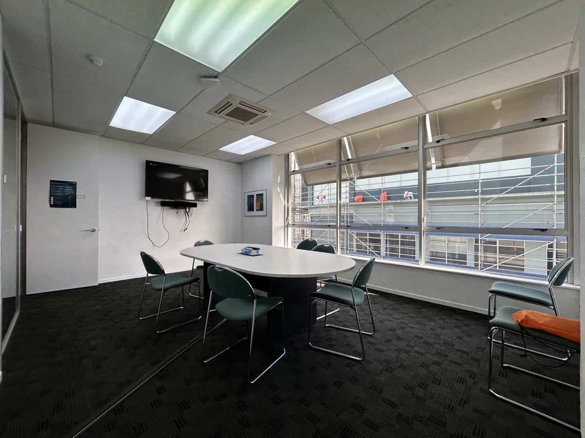 Conference room with large windows, meeting table, and office chairs.