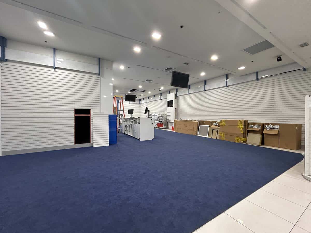 Interior of White Lion retail store with blue carpet, shelving, and checkout area.