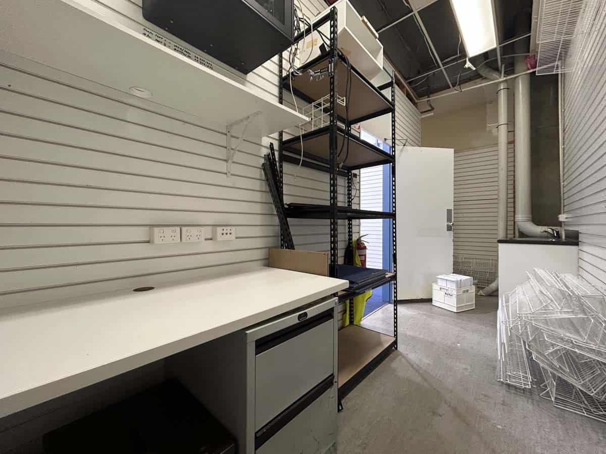 Interior of a modern office with storage shelves, work desk, and equipment.