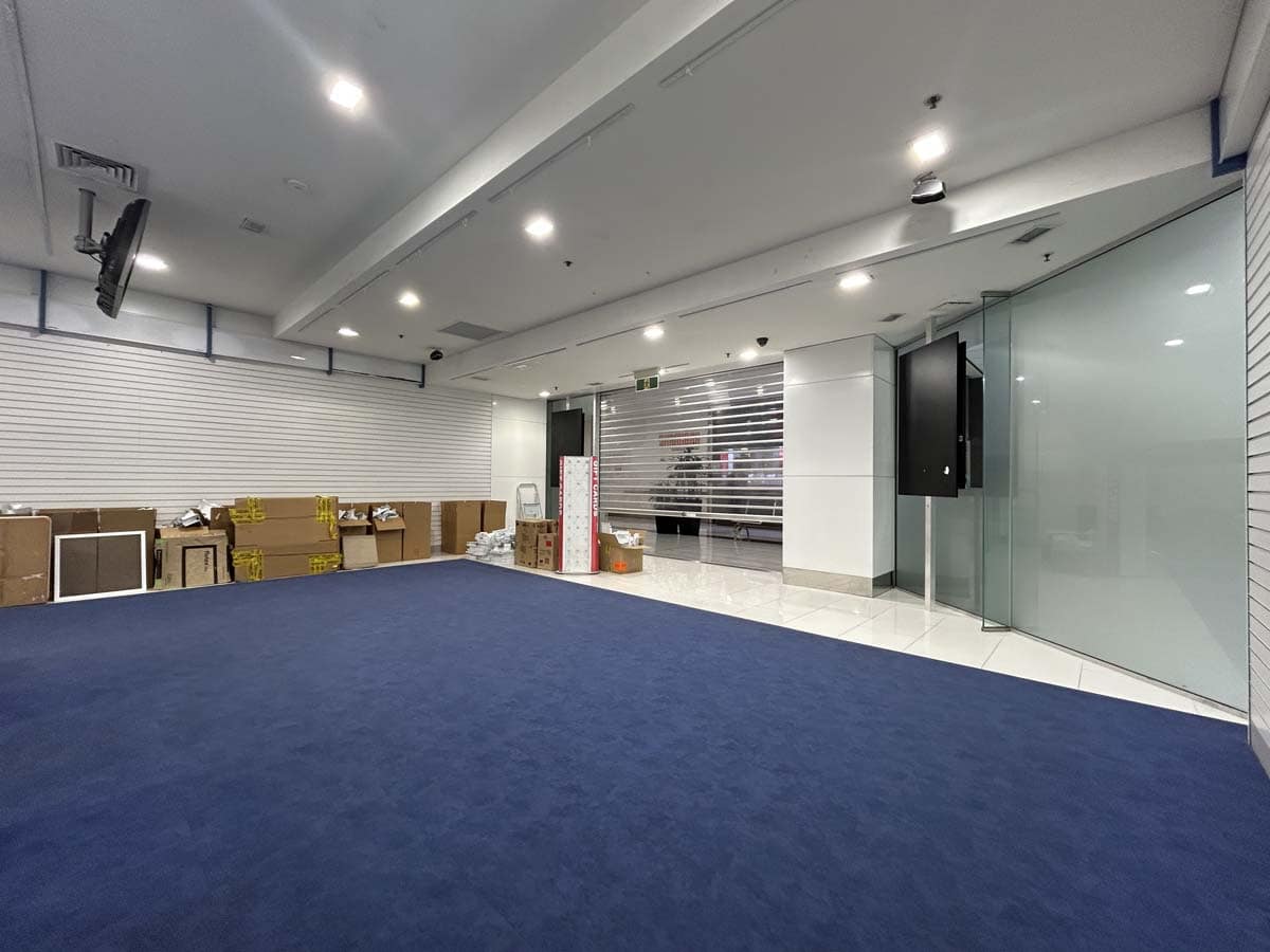 Modern office space with blue carpet and glass walls.