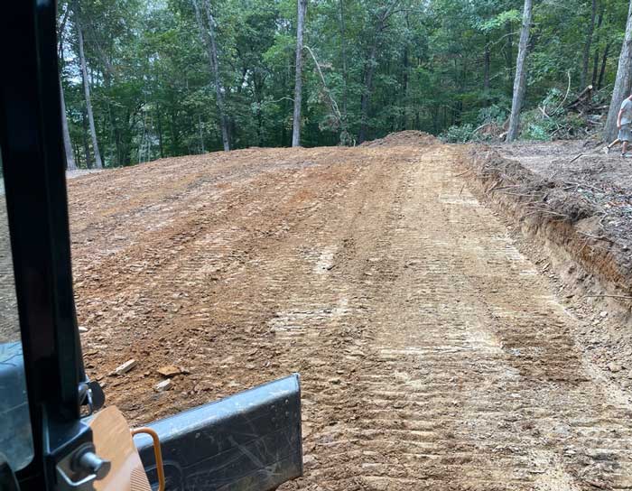 Excavation site prepared for construction with cleared and leveled land in a wooded area.