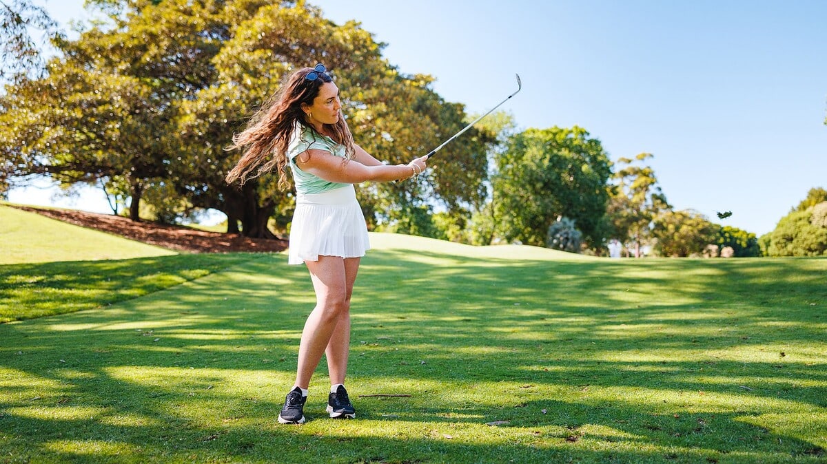 Women golfer chipping a golf ball on the fairway towards the green