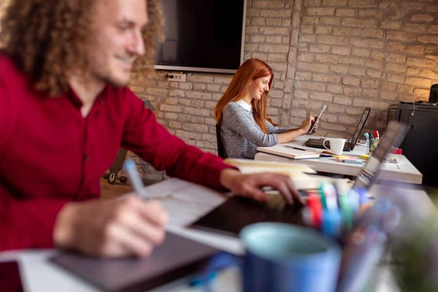 Flexible modern workspace with employees using laptops and tablets in a relaxed office setting