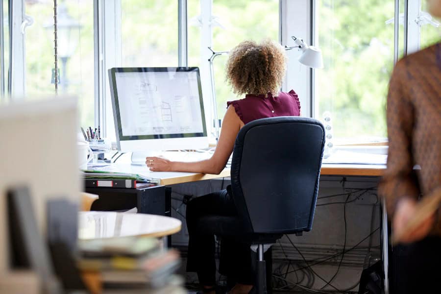 Employee working at a shared desk in a modern office, illustrating hot desking setup
