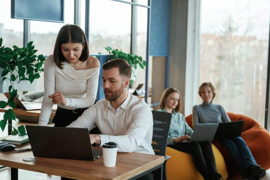 Team collaborating in a modern office, with some working at a desk and others on laptops in beanbags.