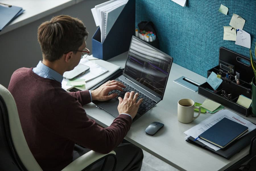 Office worker using laptop at a shared desk to manage hot desk booking software