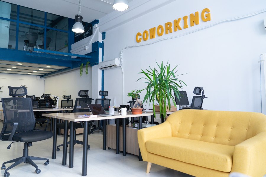 Bright coworking office with desks, yellow sofa, and open workspace.
