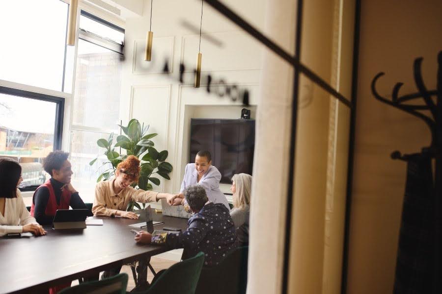 Coworking team meeting viewed through a window in a bright office.