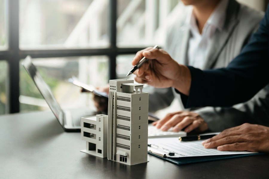 Businesspeople discussing commercial property with a model building on the desk.