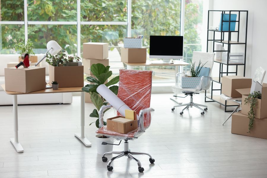 Office boxes, plants, and furniture arranged in a bright, modern workspace.