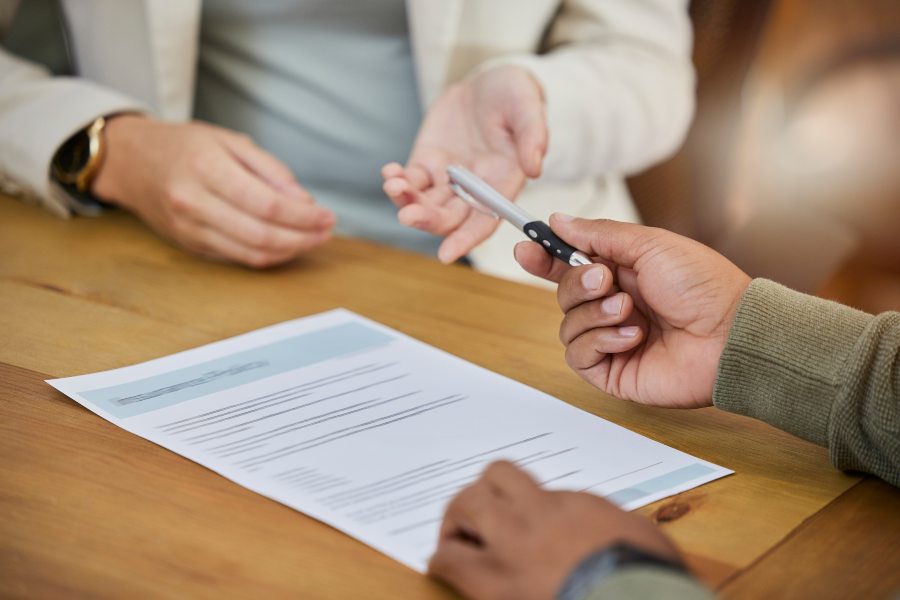 Tenant and landlord exchanging pen over document for mutual surrender of commercial lease