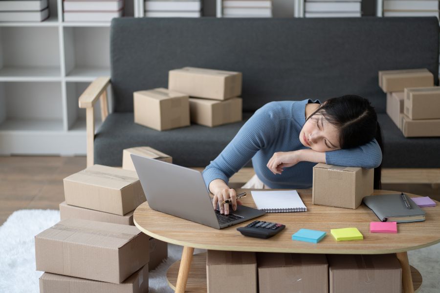 Exhausted home business owner surrounded by boxes with minimal space left.