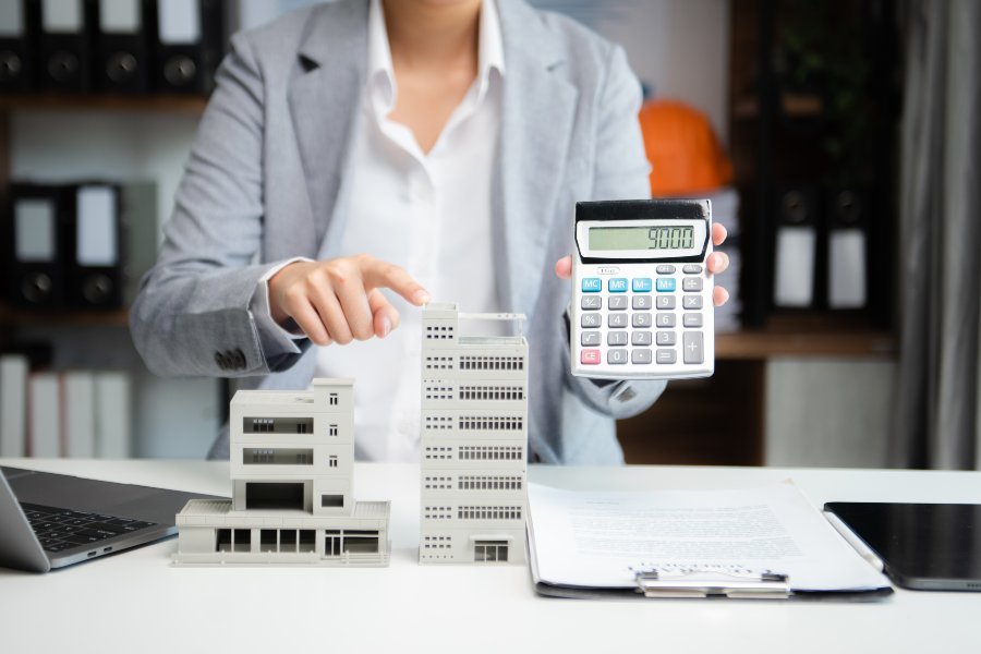Commercial property agent calculating lease costs beside a building model - understanding true expenses helps negotiate commercial rent effectively