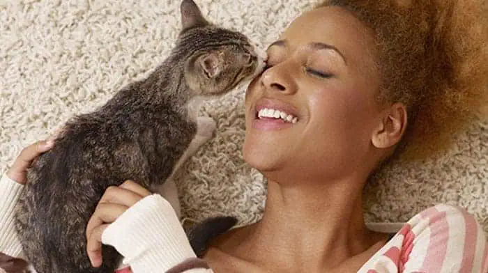 Happy woman receiving affectionate kisses from her cat, symbolizing the joy of a smooth and loving pet relocation experience