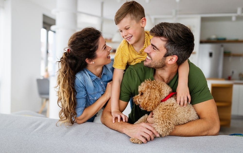 Happy family playing, having fun with dog at home.