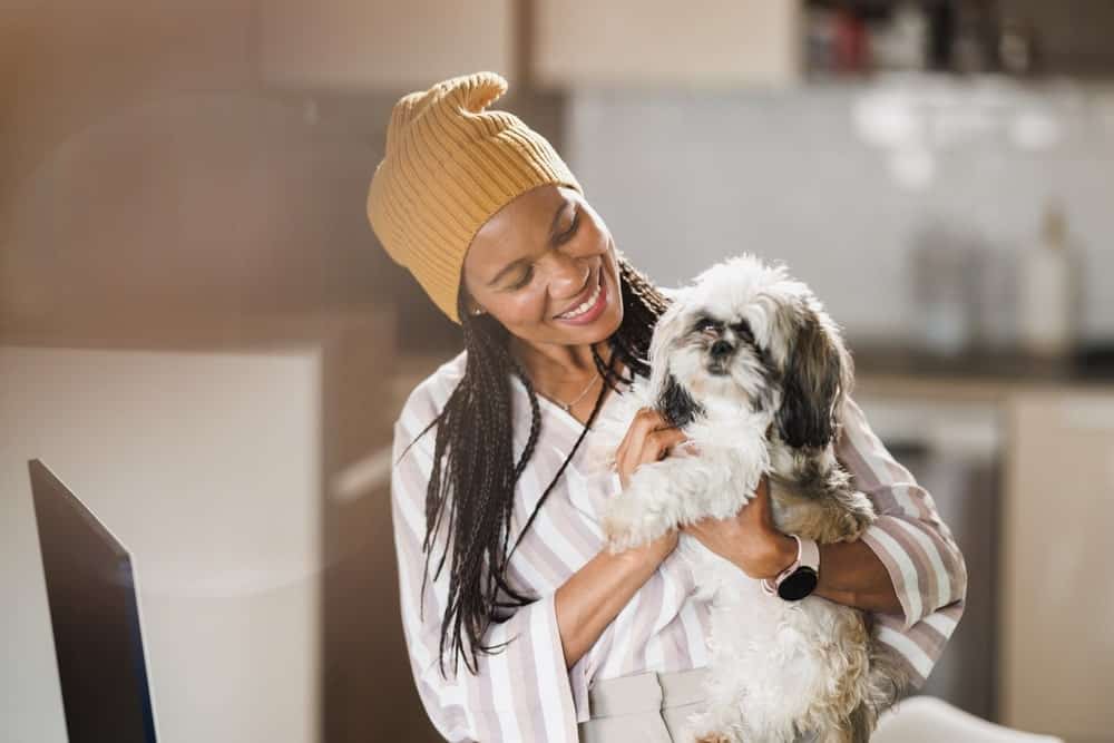 African woman smiling while working at her home office with her dog beside her — preparing for a move from the USA to Belgium.