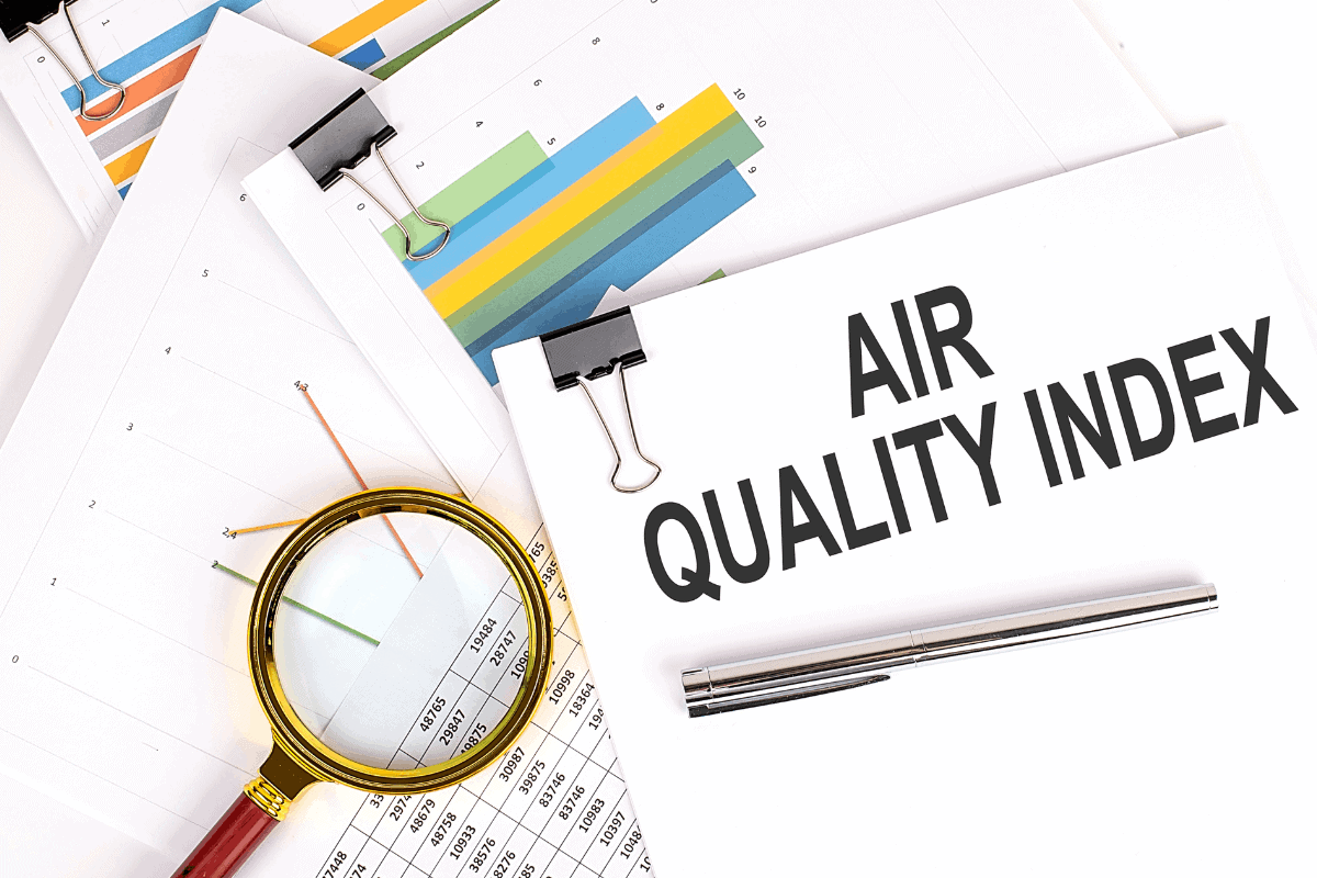 Desk scene with an 'Air Quality Index' document, colorful data charts, and a magnifying glass over statistics, representing air quality monitoring.