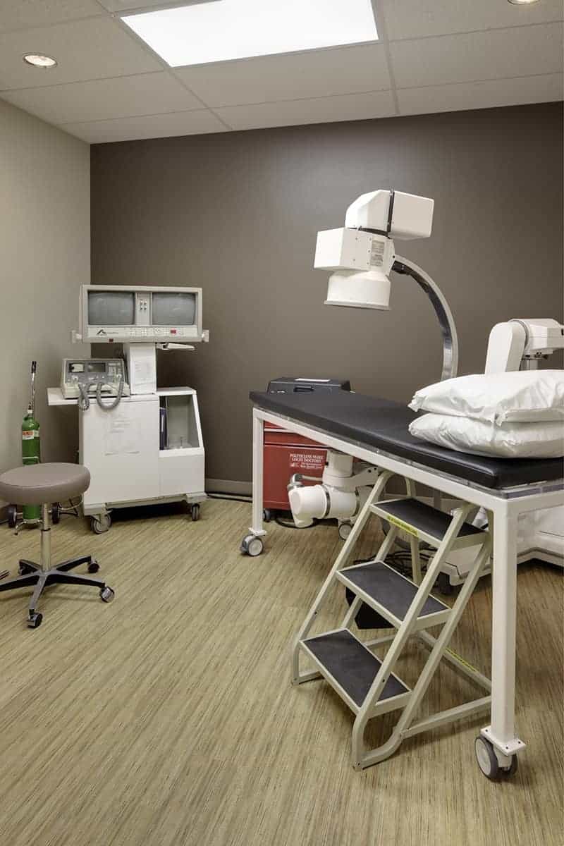 Medical examination room with equipment and bed.