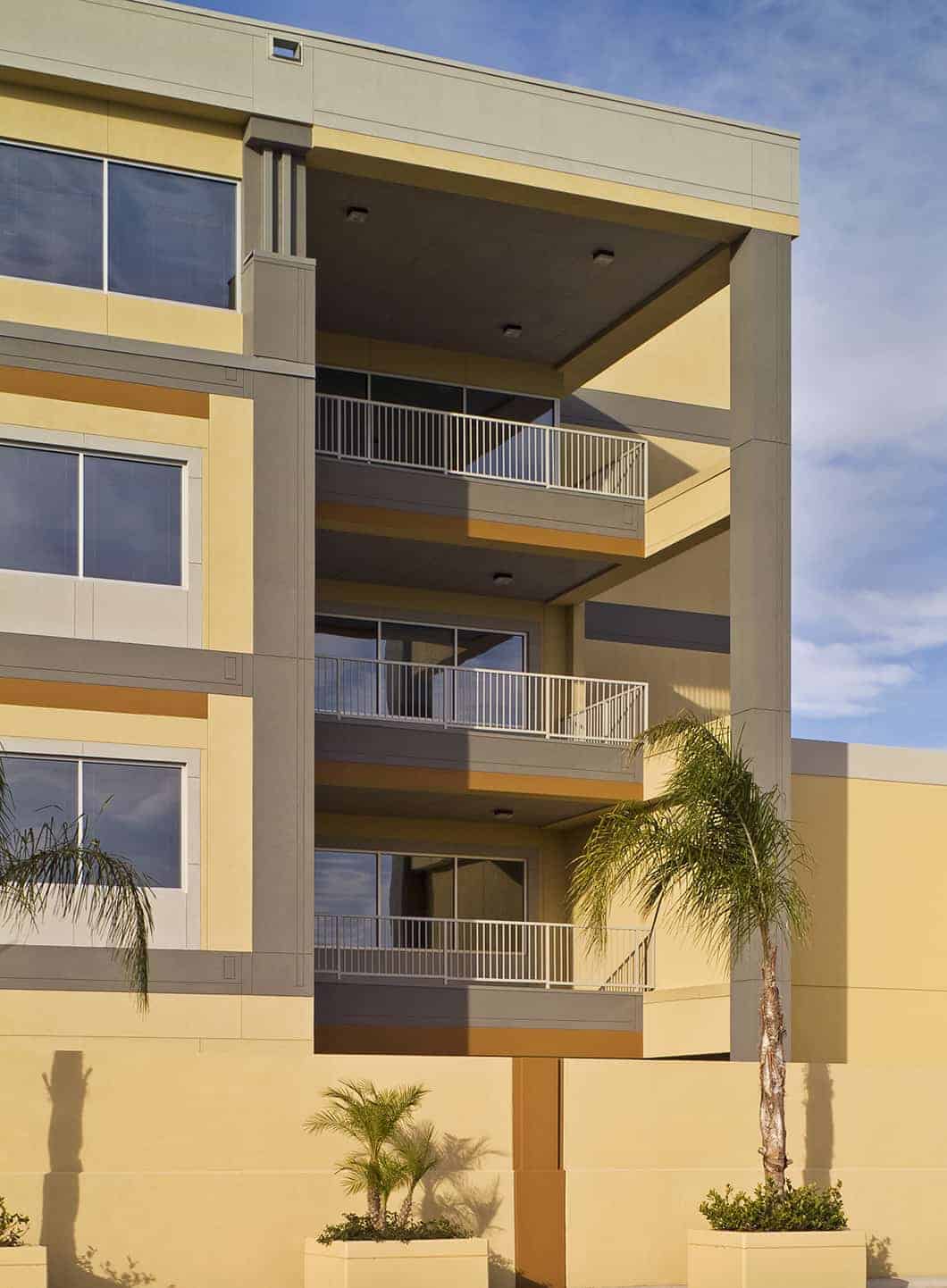 Modern building exterior with balconies and palm trees.