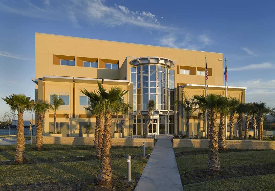 Modern building with palm trees and flags.