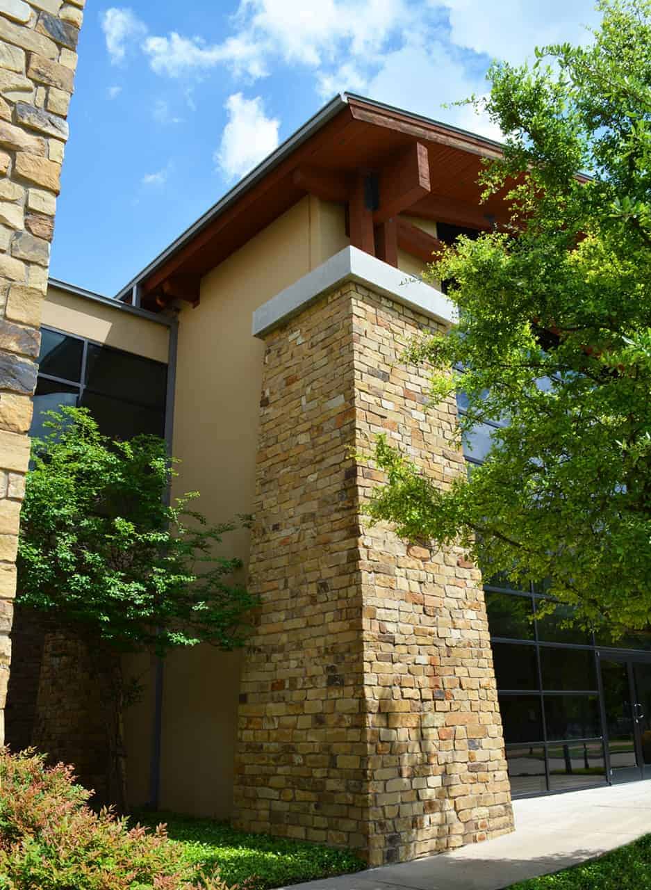 Stone building facade with trees and blue sky.