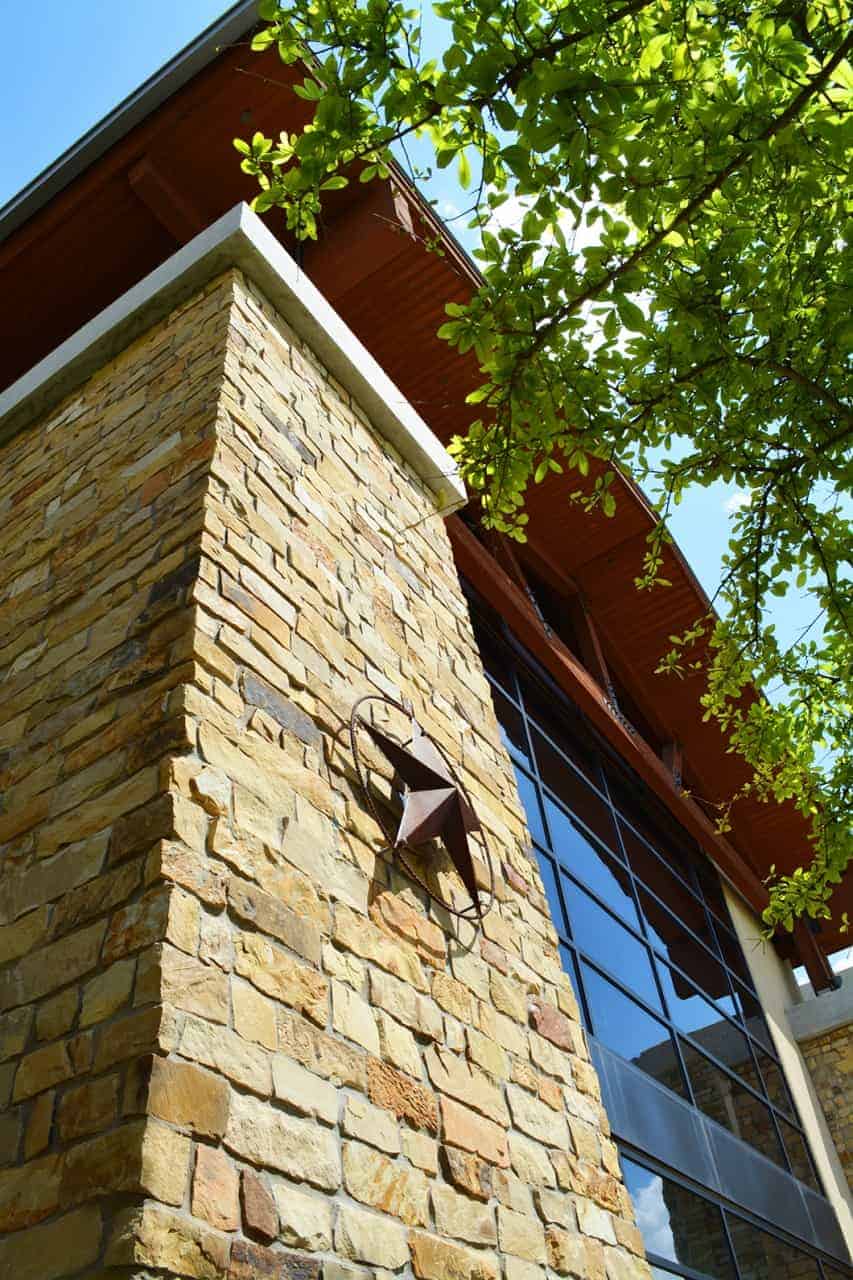 Stone building corner with star and tree leaves.