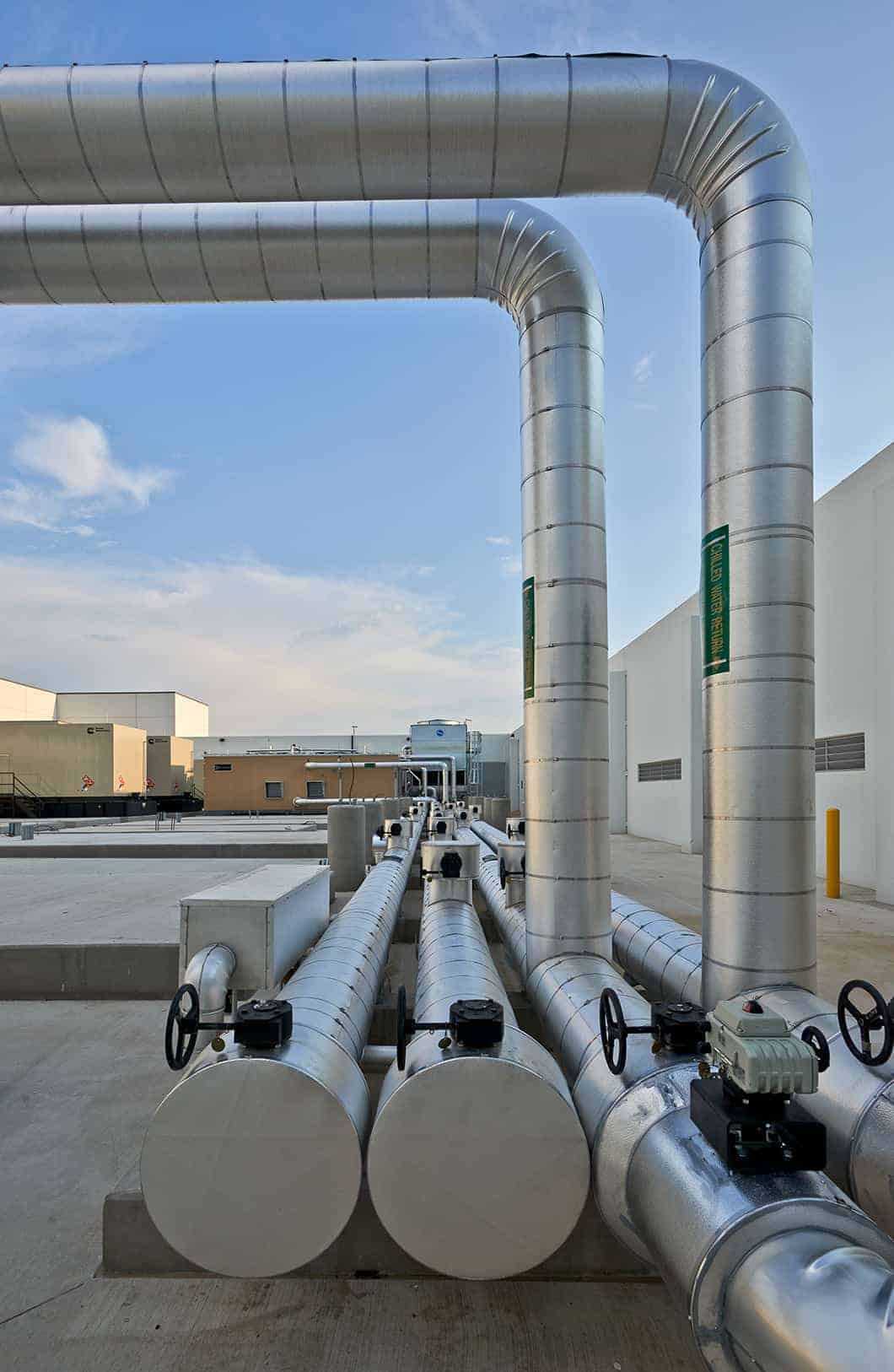 Industrial pipes on building rooftop under blue sky.