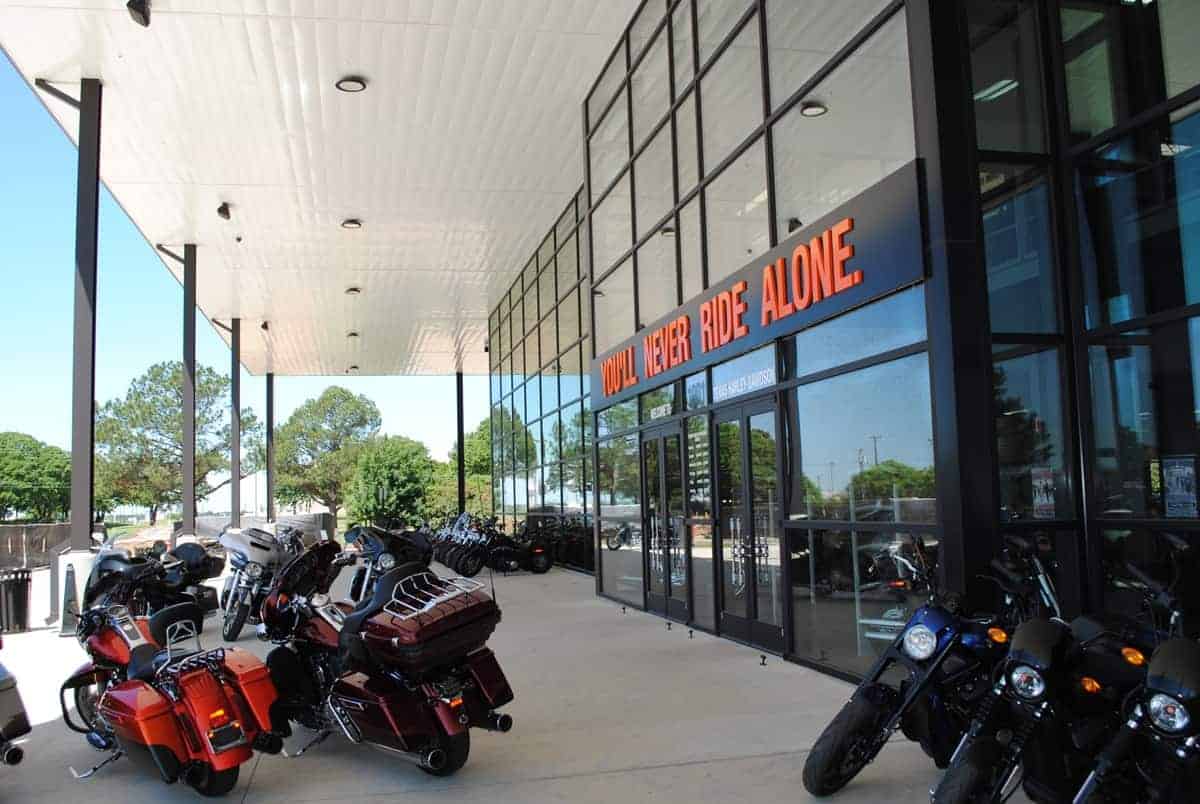 Motorcycles outside dealership with 'You'll Never Ride Alone' sign.