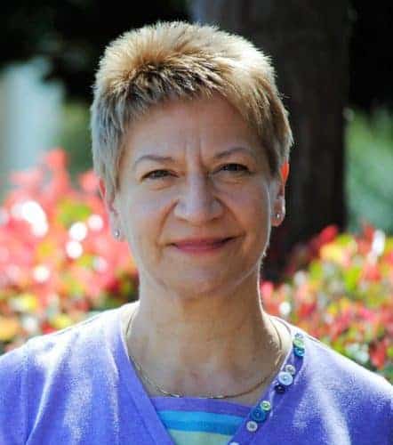 Smiling person outdoors with colorful background.