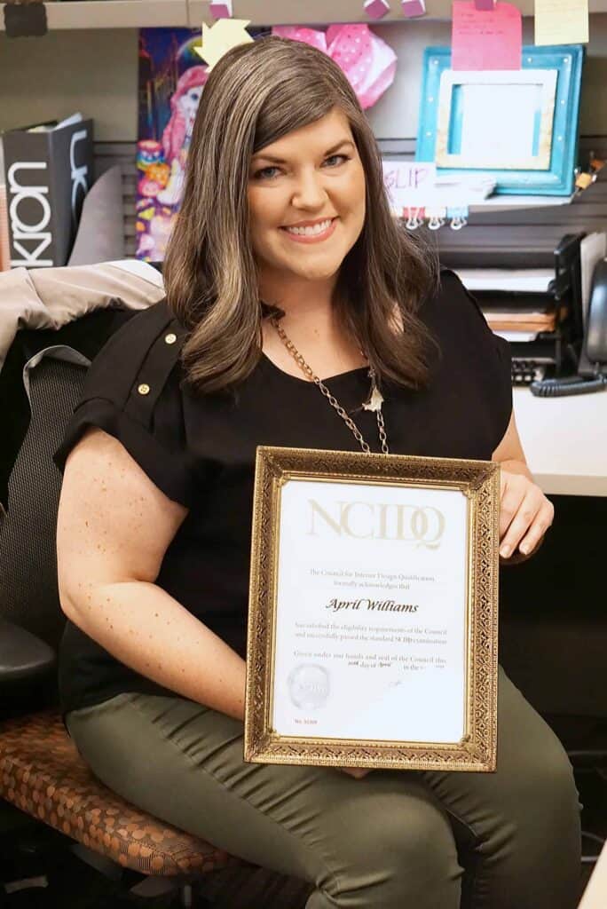 Smiling woman holds framed certificate in office.
