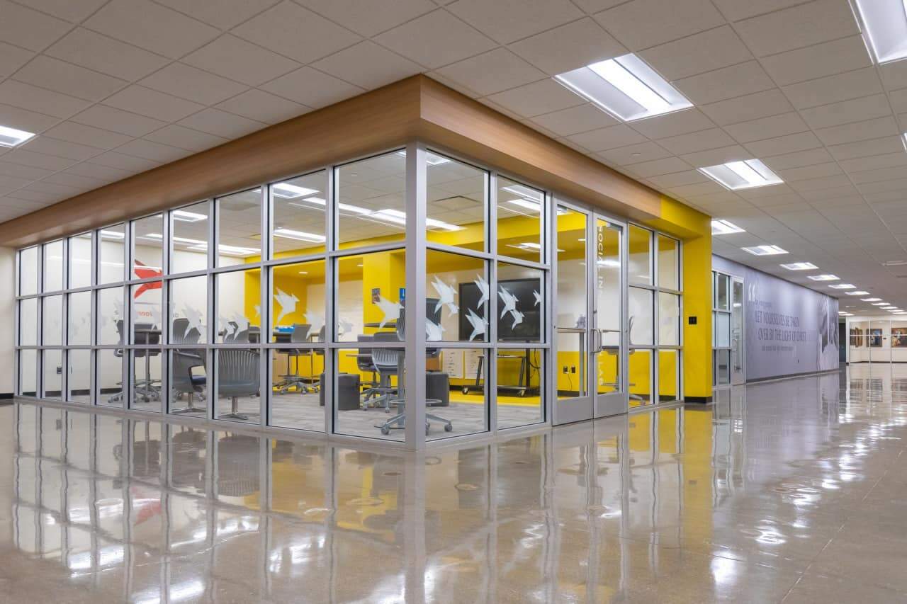 Glass-walled meeting room with yellow interior and chairs.