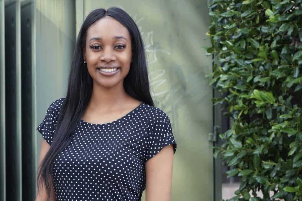 Smiling woman in a polka dot dress outside.