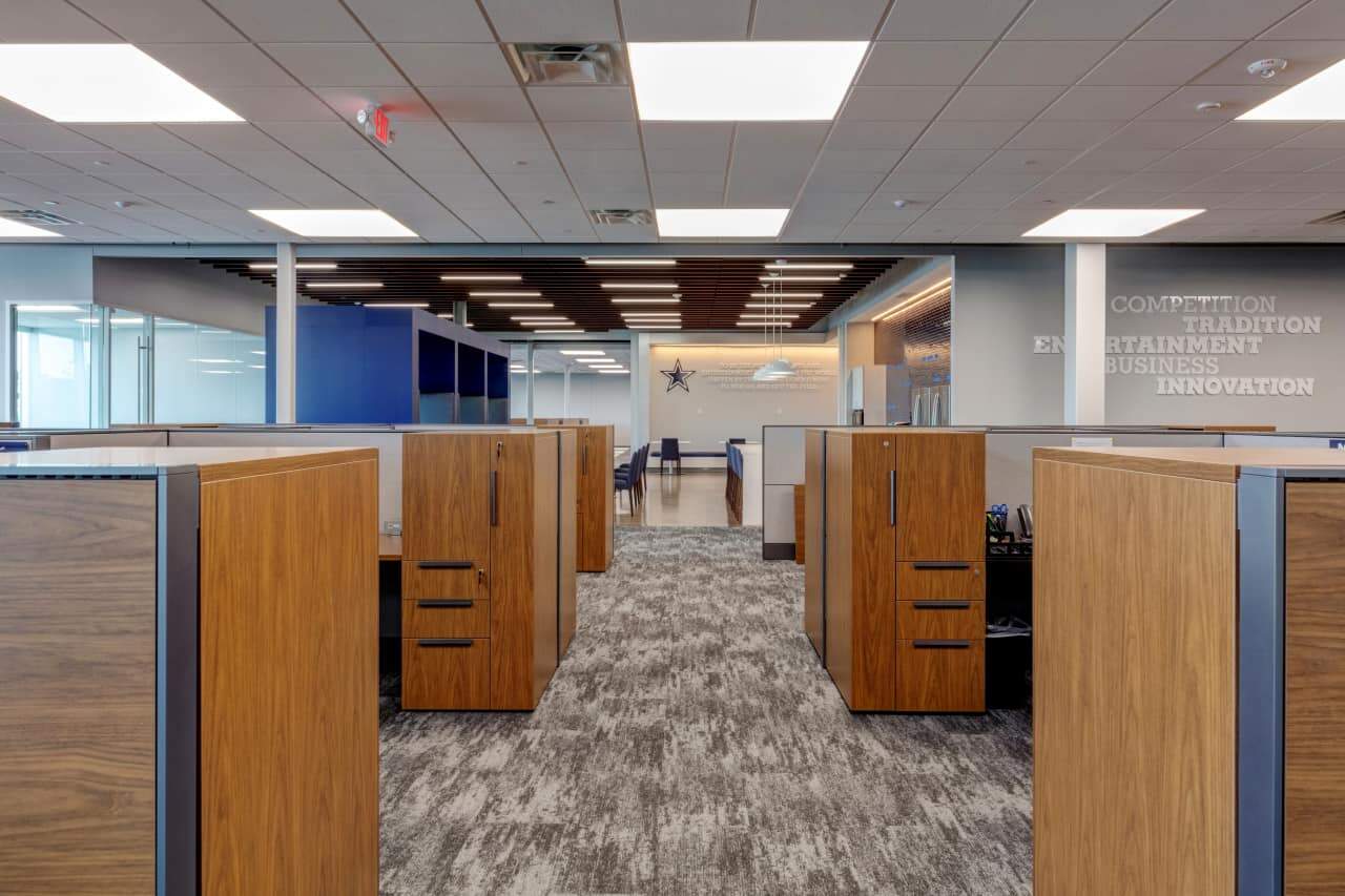 Modern office with wooden cubicles and gray carpet.