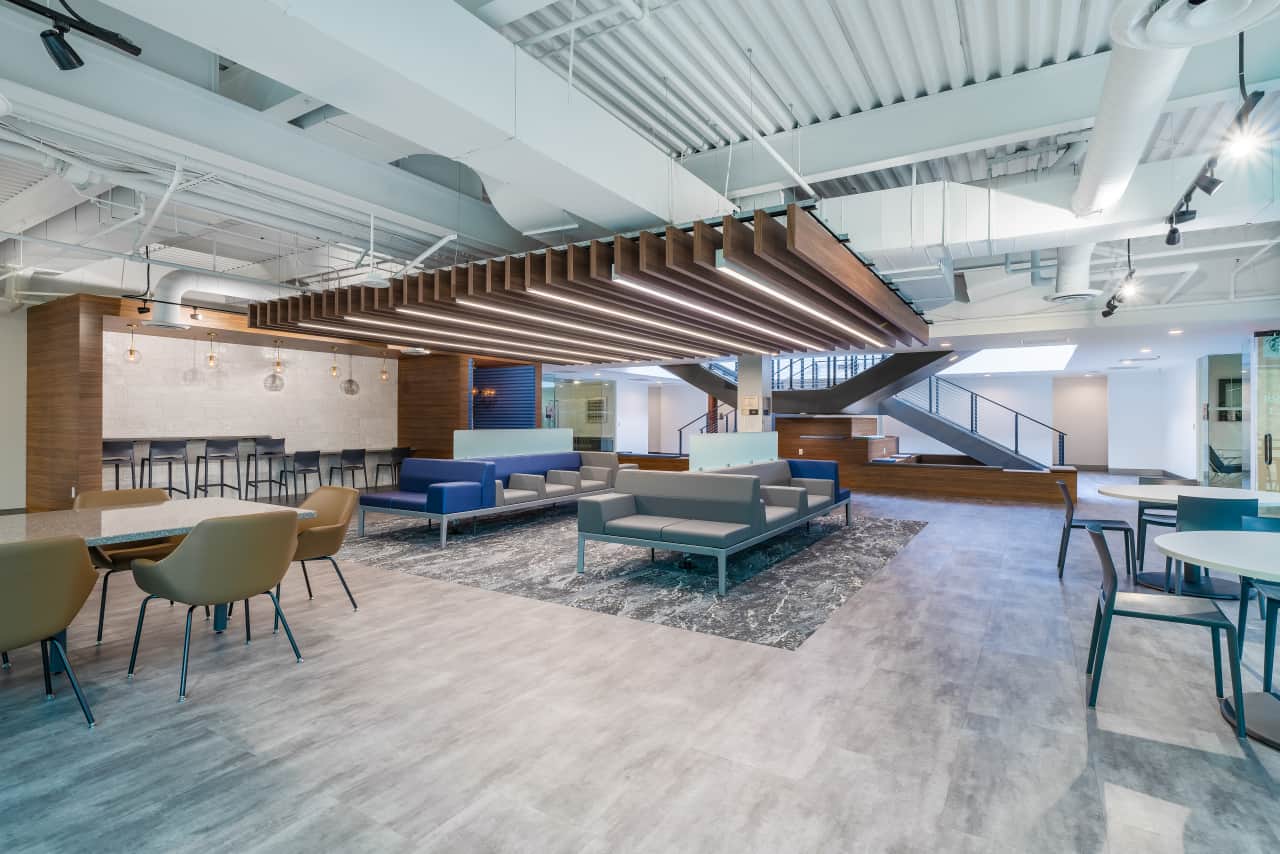 Modern office lounge area with seating and tables.