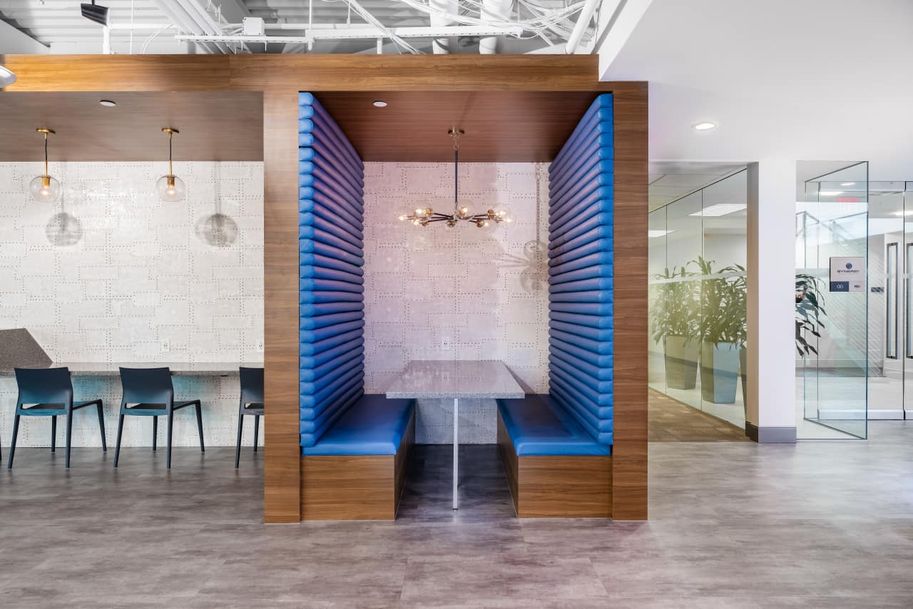 Modern office booth with blue seating and lighting.