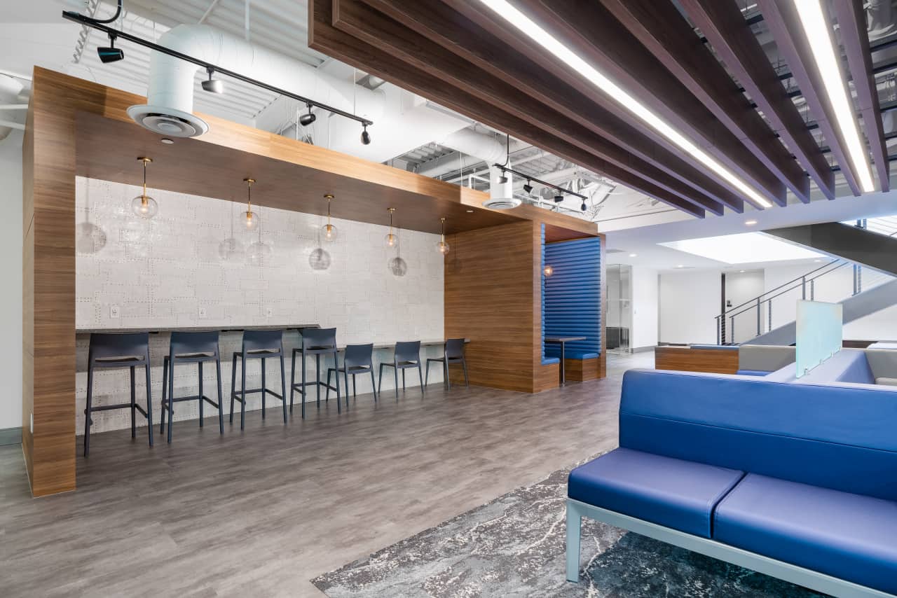 Modern office lounge with seating areas and lighting.