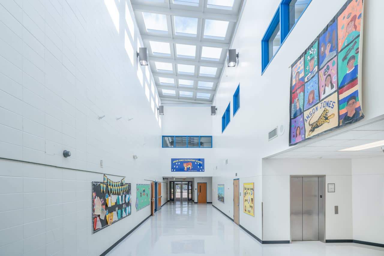 Bright school hallway with art displays and elevator.