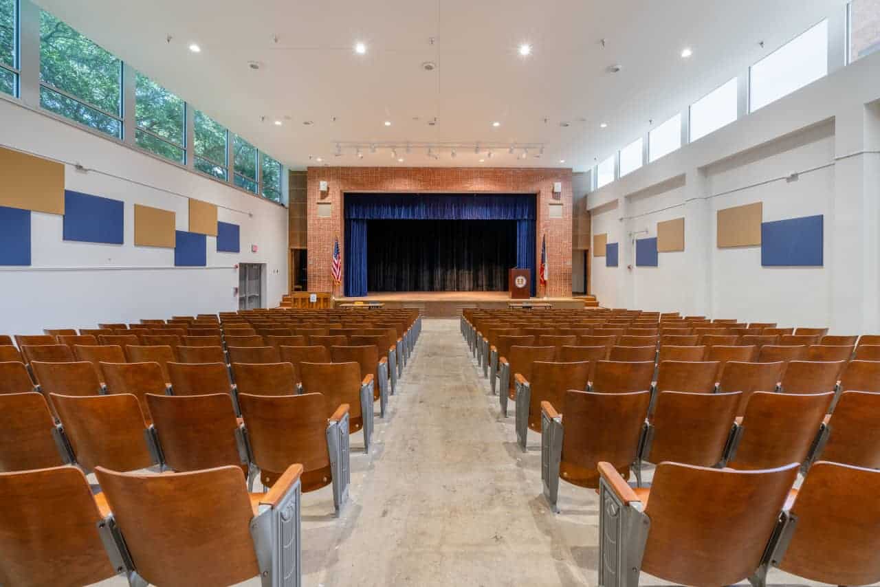 Empty auditorium with stage and rows of chairs.