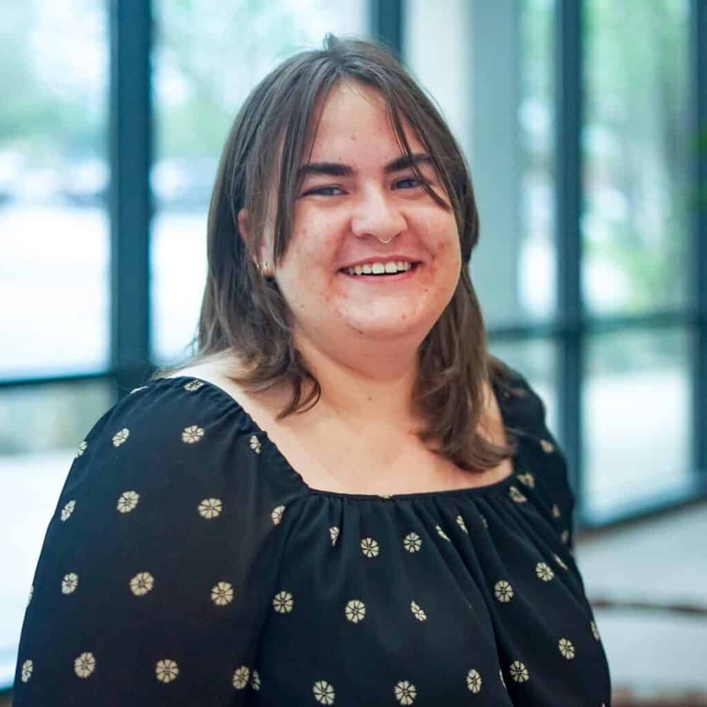 Person smiling indoors with window background
