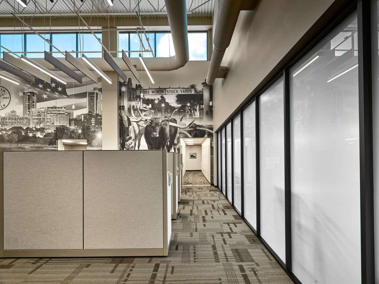 Modern office hallway with city mural and cubicles.