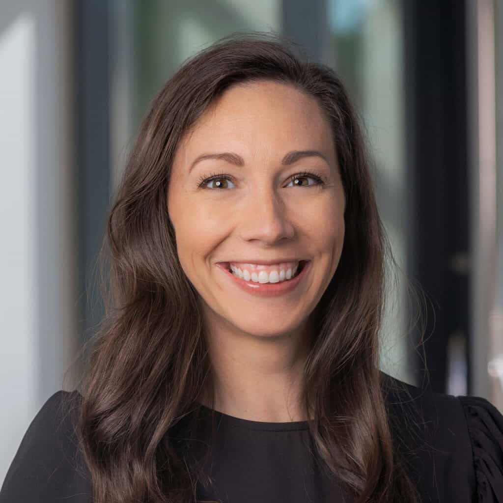 Woman smiling with long dark hair indoors.