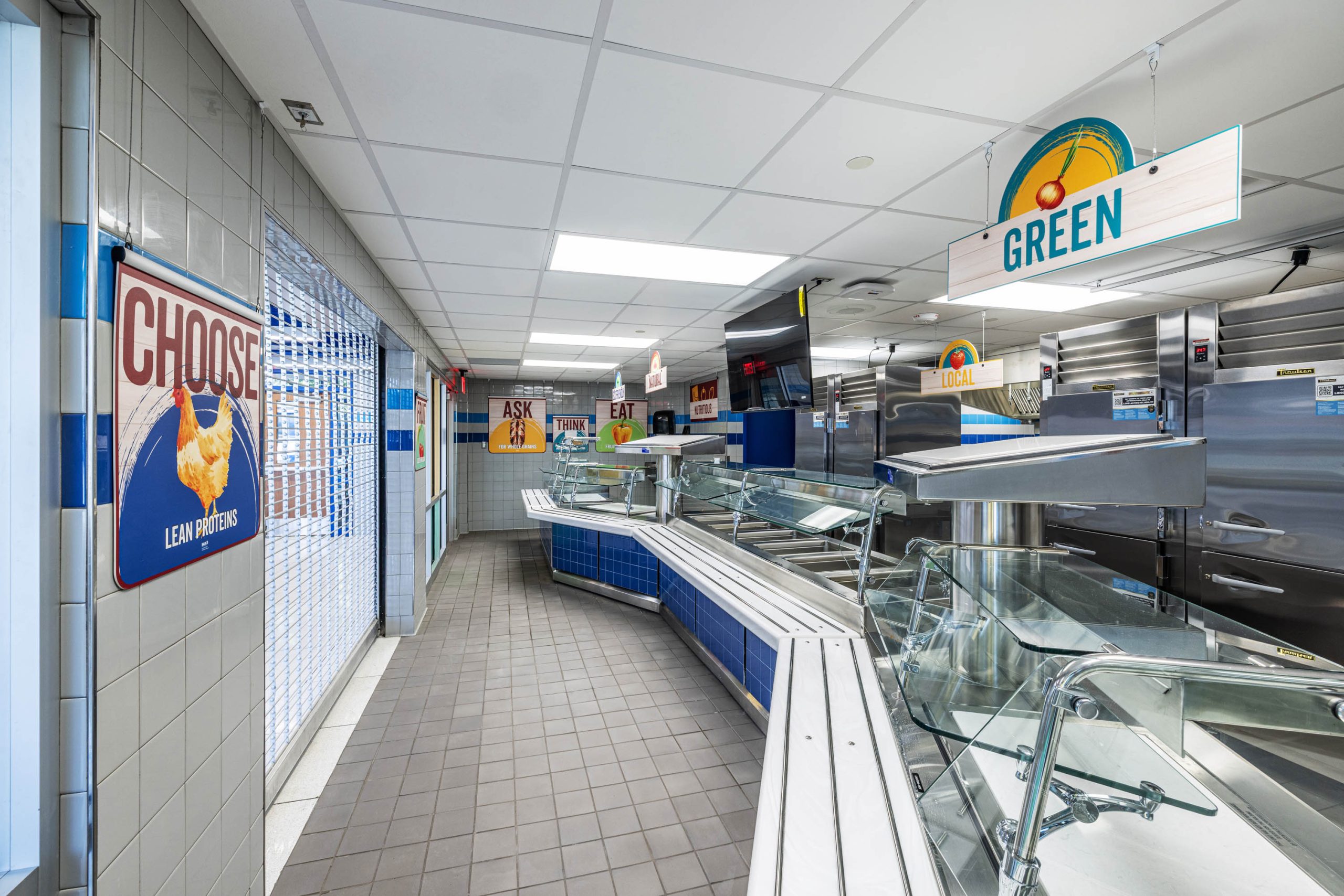 Empty cafeteria with colorful signs and serving stations.