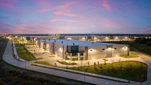 Modern industrial warehouse complex at dusk with lights