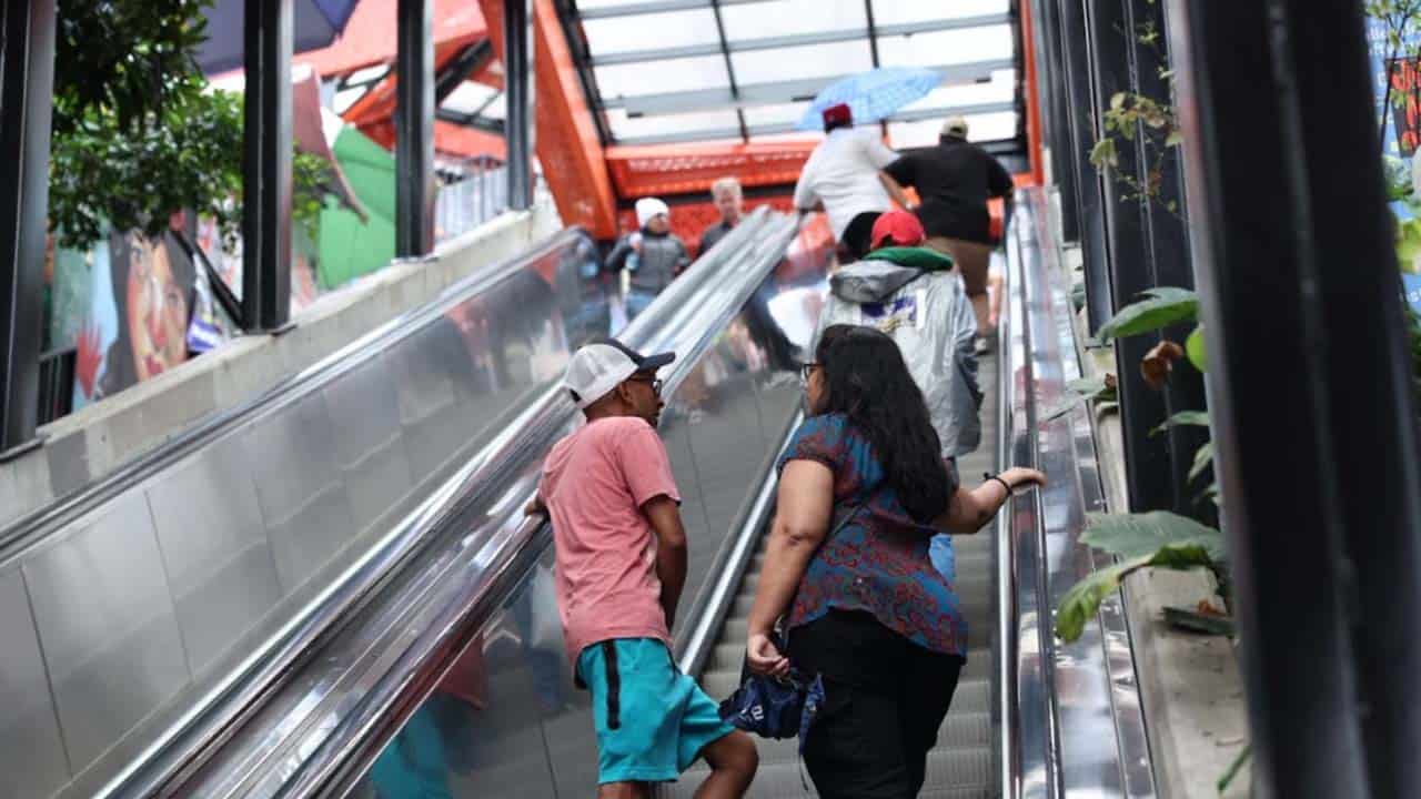 Vista de las escaleras eléctricas de la Comuna 13 en Medellín con residentes y visitantes en recorrido.